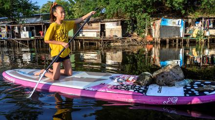 Die 12-Jährige Ralyn Satidtanasarn, Spitzname Lilly, sammelt mit ihrem Paddelbrett Plastikmüll in einem Kanal in Bangkok.