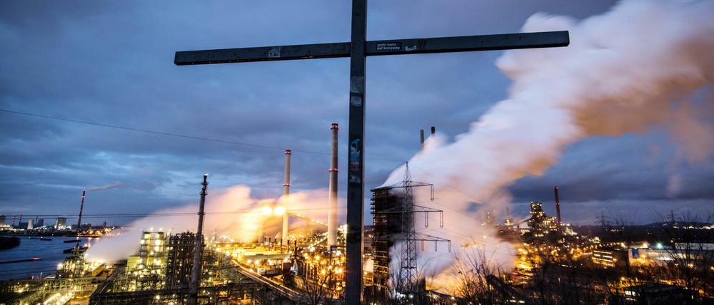 Das Thyssenkrupp Stahlwerk Schwelgern in Duisburg-Marxloh, davor ein Gipfelkreuz auf dem Alsumer Berg. Die Industrie bekommt die Konjunkturschwäche am meisten zu spüren bisher.