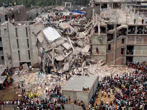 Menschen stehen um die eingestürzte Textilfabrik in Bangladesch, 2013.