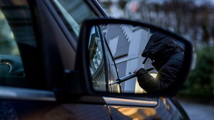 Ein Mann versucht, eine Autotür mit einer Metallstange aufzubrechen (Symbolbild). 