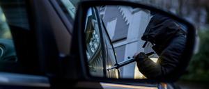 Ein Mann versucht, eine Autotür mit einer Metallstange aufzubrechen (Symbolbild). 