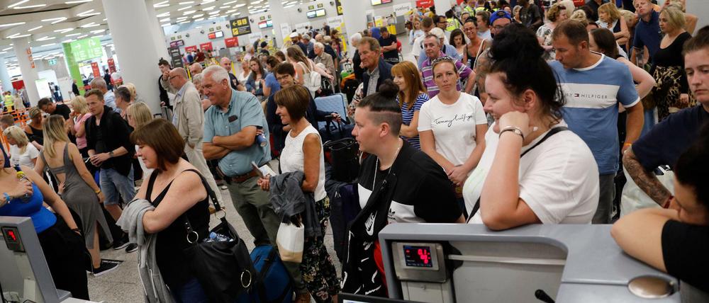 Passagiere stehen am Tag der Insolvenz des britischen Reisekonzerns Thomas Cook im Flughafen Palma de Mallorca und warten an den Check-In-Schaltern.