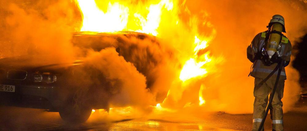 Feuerwehrleute löschen ein brennendes Auto (Symbolbild).