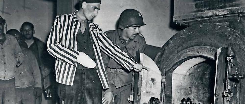 Ein polnischer Häftling zeigt einem Soldaten der US-Armee einen Krematoriumsofen.