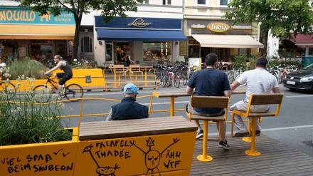 Passanten sitzen in einem Parklet an der Bergmannstraße in Kreuzberg.
