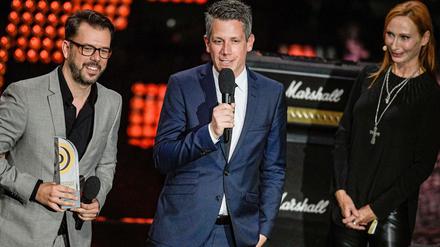 Schauspielerin Andrea Sawatzki, Schauspielerin steht als Laudatorin während der Verleihung des 10. Deutschen Radiopreises auf der Bühne neben Marc Haberland und Vivian Pickelmann (links) von 104.6 RTL, die den Preis in der Kategorie "Beste Innovation" gewonnen haben.