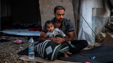 Ein Mann sitzt mit einem Kind vor einer Unterkunft im Flüchtlingslager Moria auf der griechischen Insel Lesbos.