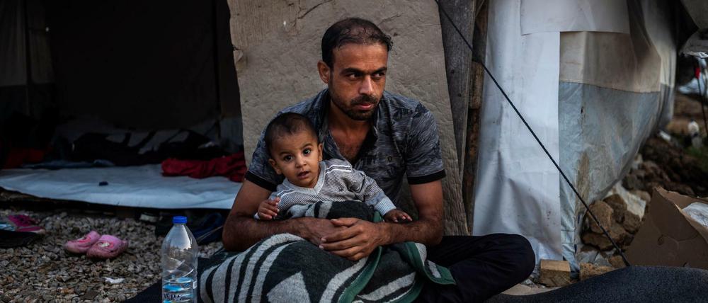 Ein Mann sitzt mit einem Kind vor einer Unterkunft im Flüchtlingslager Moria auf der griechischen Insel Lesbos.