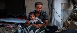 Ein Mann sitzt mit einem Kind vor einer Unterkunft im Flüchtlingslager Moria auf der griechischen Insel Lesbos.