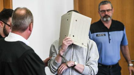 Silvio S. geht mit einer Aktenmappe vor seinem Gesicht in einen Verhandlungssaal des Landgerichtes Potsdam.