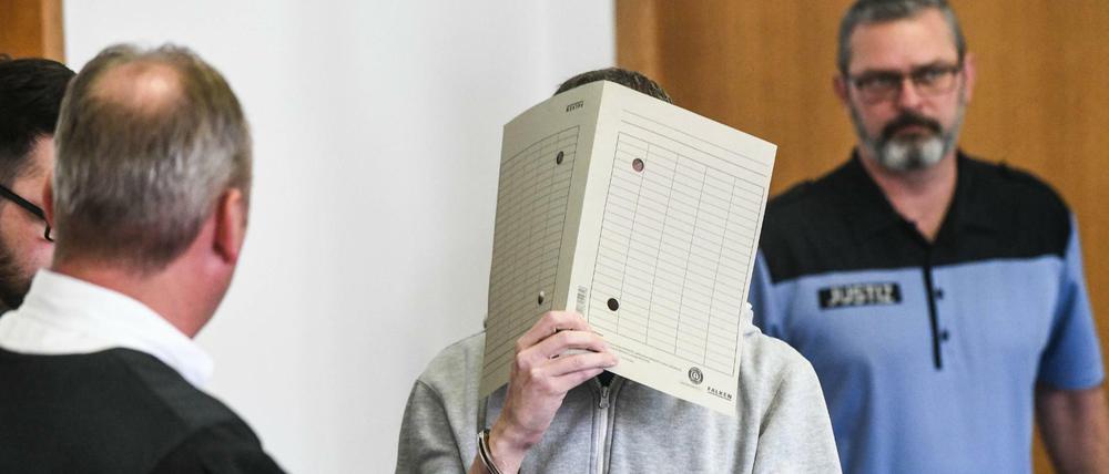 Silvio S. geht mit einer Aktenmappe vor seinem Gesicht in einen Verhandlungssaal des Landgerichtes Potsdam.
