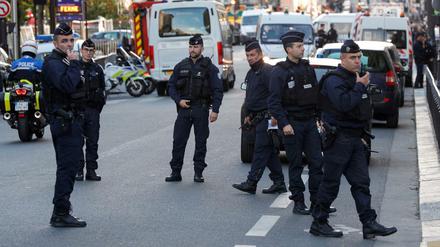Polizisten stehen in der Nähe des Tatorts auf der Straße.
