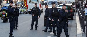 Polizisten stehen in der Nähe des Tatorts auf der Straße.