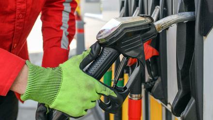 Ein Tankwart nimmt eine Zapfpistole aus der Halterung einer Zapfsäule einer Tankstelle.