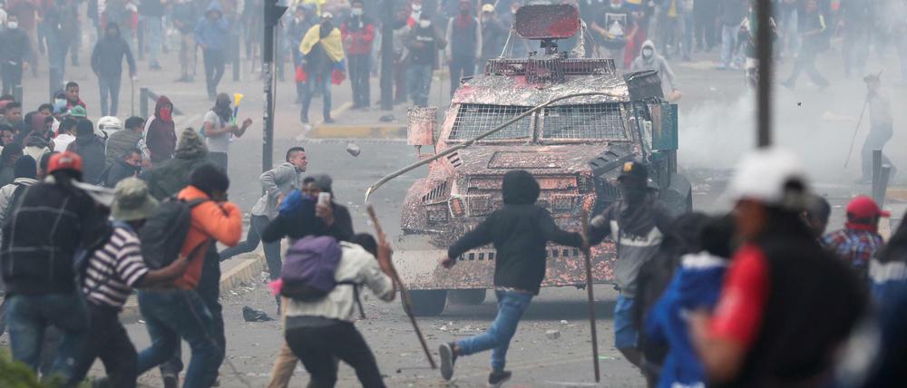 Demonstranten in Quito greifen ein Polizeifahrzeug an.