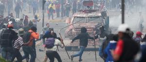 Demonstranten in Quito greifen ein Polizeifahrzeug an. 