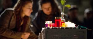 Zwei Frauen zünden eine Kerze auf dem Marktplatz zum Gedenken an die Opfer an. 