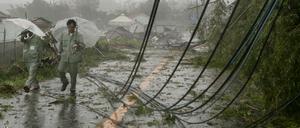 Zwei Männer laufen entlang heruntergerissener Stromkabel. 