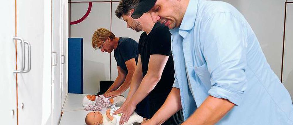 Die werdenden Väter üben das Wickeln an Puppen. 
