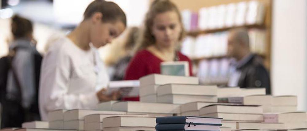 Besucherinnen blättern auf der Frankfurter Buchmesse durch Neuerscheinungen.