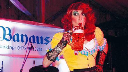 Drag Queen Mataina Ah-wie-süss trinkt Maß mit Strohhalm. 