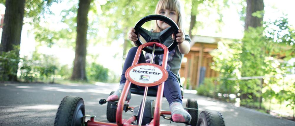 Ein Mädchen sitzt auf einem Kettcar des Herstellers Kettler.