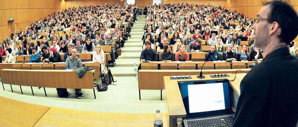 Ein Dozent steht in einem vollbesetzten Hörsaal vor Studierenden.