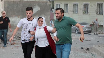 Nachbarn bringen eine Frau in Sicherheit, nachdem eine Rakete aus Syrien in der türkischen Grenzstadt Nusaybin eingeschlagen ist.