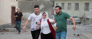 Nachbarn bringen eine Frau in Sicherheit, nachdem eine Rakete aus Syrien in der türkischen Grenzstadt Nusaybin eingeschlagen ist.