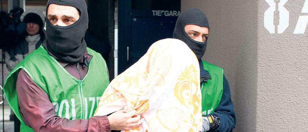 Polizisten führen bei einer Razzia gegen Islamisten einen Verdächtigen ab.