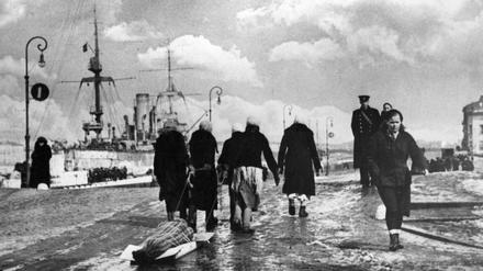In Leningrad ziehen Frauen während der deutschen Blockade im Zweiten Weltkrieg eine verhüllte Leiche zum Friedhof.