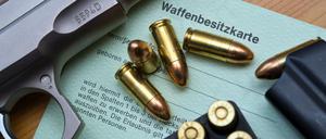 Eine Kaliber 9 mm Pistole, Patronen und ein Magazin liegen auf einer Waffenbesitzkarte.
