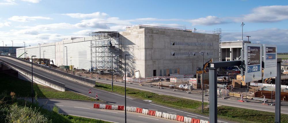 Das im Bau befindliche Terminal 2 des Hauptstadtflughafen Berlin Brandenburg hinter einer Zufahrtsstraße.
