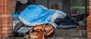 Ein Obdachloser liegt unter einer Decke in einem Eingang einer Kirche in Kreuzberg.