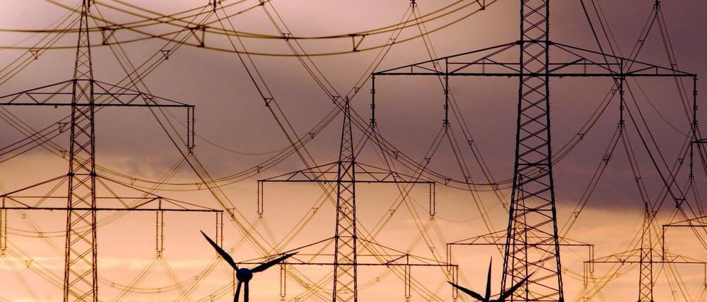 Strommasten und Windräder heben sich wie Scherenschnitte vom farbenprächtigen Abendhimmel in Brandenburg ab