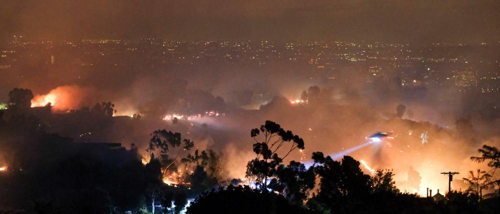 Ein Hubschrauber fliegt über einem Wohngebiet, das vom sogenannten Getty-Feuer betroffen ist.