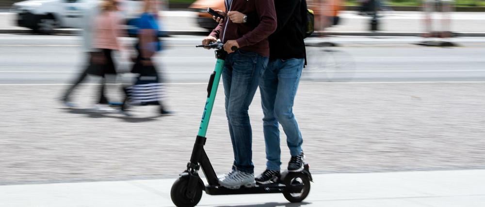 Zwei Touristen fahren auf einem E-Roller der Marke „Tier“ durch Berlin-Mitte.
