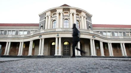 Ein schwarz gekleideter Passant vor dem Hauptgebäude der Universität Hamburg.