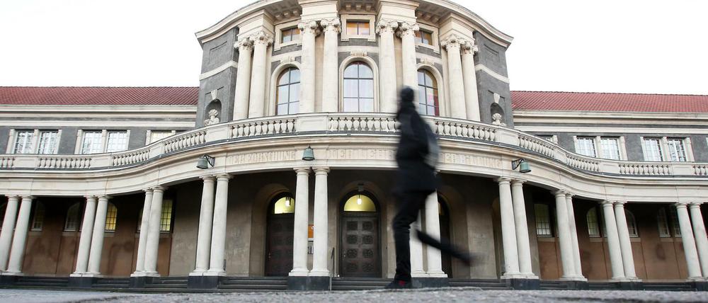 Ein schwarz gekleideter Passant vor dem Hauptgebäude der Universität Hamburg.