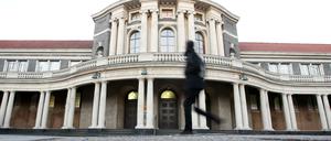 Ein schwarz gekleideter Passant vor dem Hauptgebäude der Universität Hamburg.