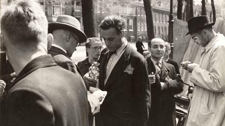 Mitarbeiter des Bureau Joodse Zaken (Amt für Jüdische Angelegenheiten) der Amsterdamer Polizei überprüfen die Personalausweise jüdischer Händler auf dem Briefmarkenmarkt am Nieuwezijds Voorburgwal in Amsterdam.Sommer 1942.