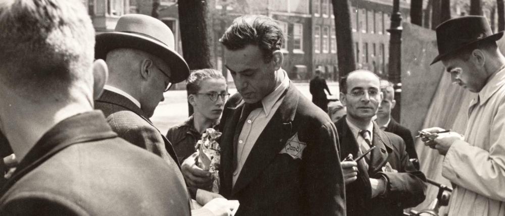 Mitarbeiter des Bureau Joodse Zaken (Amt für Jüdische Angelegenheiten) der Amsterdamer Polizei überprüfen die Personalausweise jüdischer Händler auf dem Briefmarkenmarkt am Nieuwezijds Voorburgwal in Amsterdam.Sommer 1942.