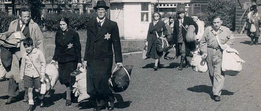 Vor aller Augen. Am Morgen des 20. Juni 1943, einem Sonntag, finden in Amsterdam große Razzien statt. Ganze Stadtviertel werden abgeriegelt und Juden werden aufgefordert, sich zu Sammelplätzen zu begeben. Viele Juden haben diese Aktion erwartet; ihr Gepäck steht schon an der Tür bereit. Familien kommen hier mit schwerem Gepäck zum Sportpark auf dem Olympiaplein, dem Sammelplatz im Süden von Amsterdam.Foto: Herman Heukels NIOD