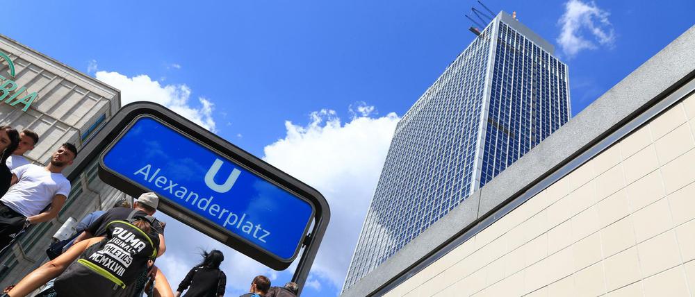 Passanten am U-Bahnhof und dem Hochhaus vom Hotel Park-Inn auf dem Alexanderplatz in Berlin-Mitte.