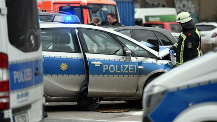 Ein Feuerwehrmann steht nach einem Unfall an einem beschädigten Polizeiauto.