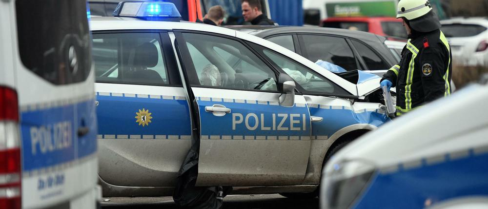 Ein Feuerwehrmann steht nach einem Unfall an einem beschädigten Polizeiauto.