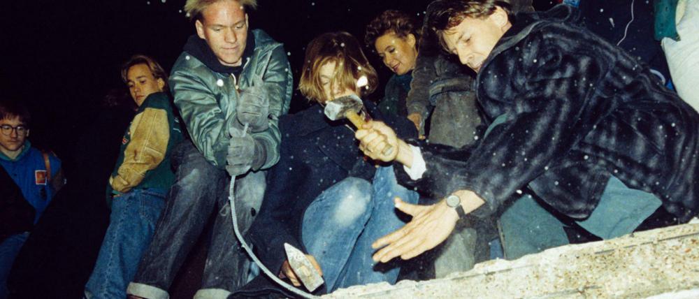 West-Berliner versuchen im November 1989 mit Hämmern und Kreuzhacken die Berliner Mauer einzureißen.