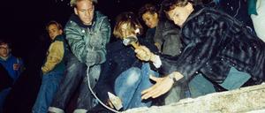 West-Berliner versuchen im November 1989 mit Hämmern und Kreuzhacken die Berliner Mauer einzureißen.