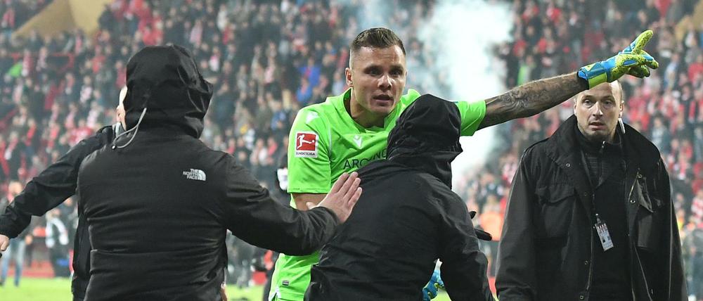 Vermummte Union-Hooligans stürmen das Spielfeld, doch Union-Torwart Rafal Gikiewicz stellt sich ihnen entgegen.