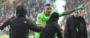 Vermummte Union-Hooligans stürmen das Spielfeld, doch Union-Torwart Rafal Gikiewicz stellt sich ihnen entgegen.